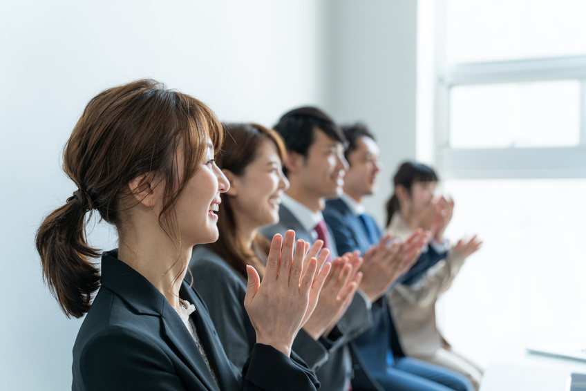 昇進の挨拶に拍手でこたえる部下たち