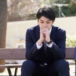 公園で悩んでいるビジネスマン
