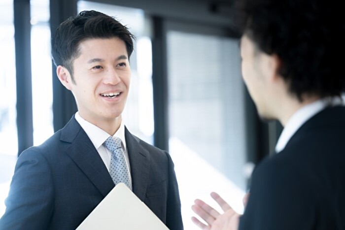 同僚と朗らかに会話するビジネスパーソンのイメージ画像