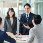 社内で会話する若手ビジネスパーソンイメージ画像